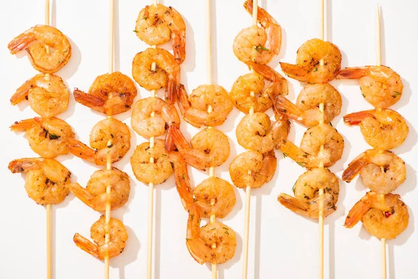 Vista superior de deliciosos langostinos fritos en brochetas sobre fondo blanco - foto de stock