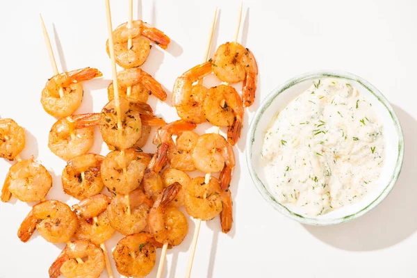 Vue de dessus de délicieuses crevettes frites sur brochettes avec sauce sur fond blanc — Photo de stock