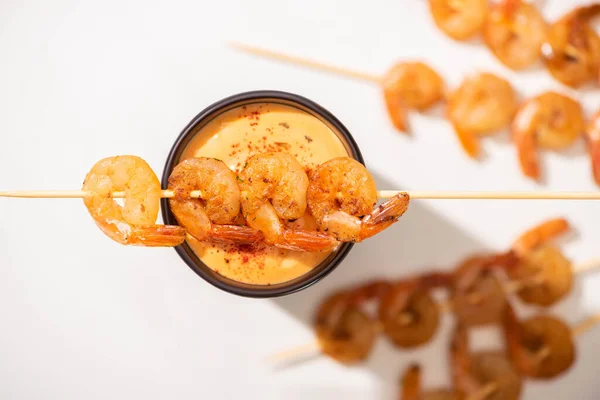 Enfoque selectivo de deliciosos langostinos fritos en pincho con salsa sobre fondo blanco - foto de stock