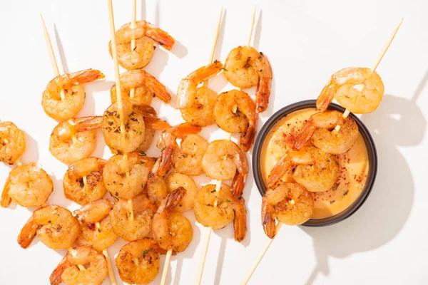 Vista superior de deliciosos langostinos fritos en pinchos con salsa sobre fondo blanco - foto de stock