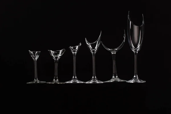 Broken sharp transparent glasses in row isolated on black — Stock Photo