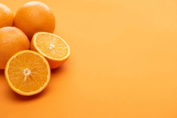 Corte delicioso maduro e laranjas inteiras no fundo colorido — Fotografia de Stock