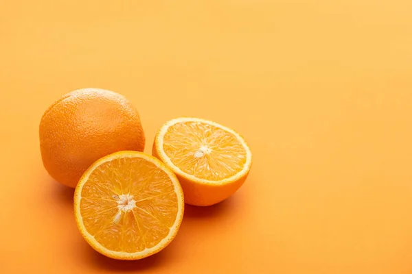 Corte delicioso maduro e laranjas inteiras no fundo colorido — Fotografia de Stock