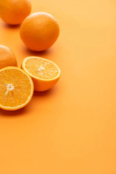 Ripe delicious cut and whole oranges on colorful background — Stock Photo