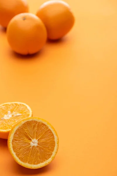 Selective focus of ripe juicy whole and cut oranges on colorful background — Stock Photo