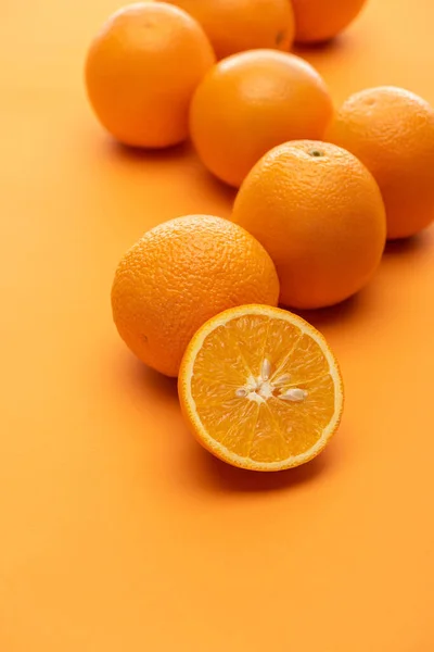 Foco selectivo de naranjas maduras jugosas enteras y cortadas sobre fondo colorido - foto de stock