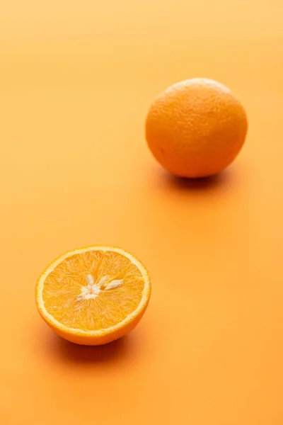 Ripe juicy whole and cut oranges on colorful background — Stock Photo