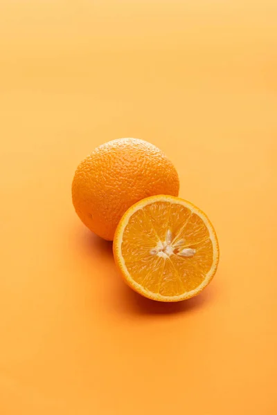 Ripe juicy whole and cut oranges on colorful background — Stock Photo