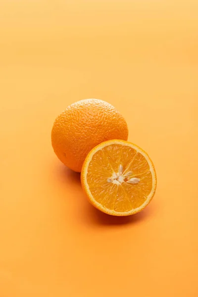 Maduras jugosas naranjas enteras y cortadas sobre fondo colorido - foto de stock