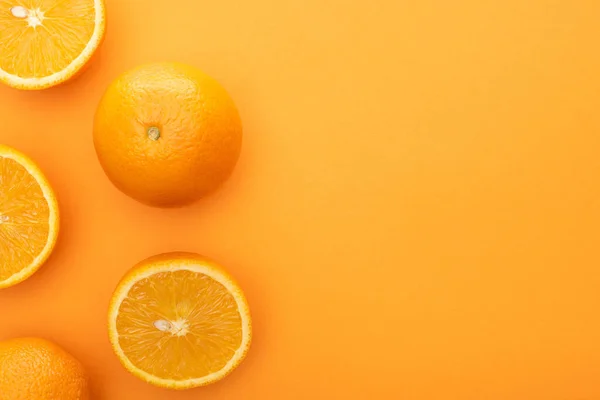 Vista superior de jugosas naranjas enteras y rebanadas sobre un fondo colorido - foto de stock