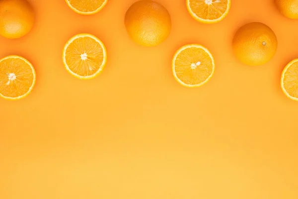 Vue de dessus des oranges entières juteuses mûres et des tranches sur fond coloré — Photo de stock