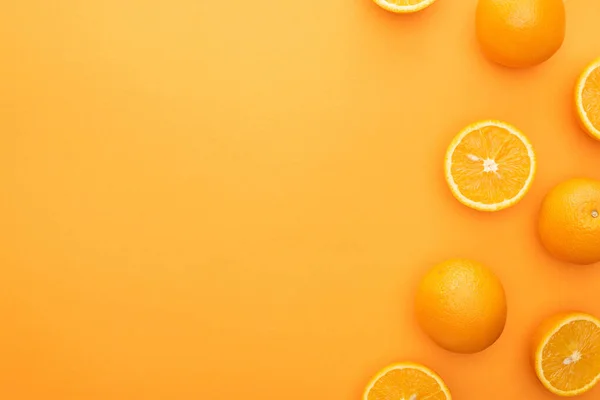 Vista superior de naranjas enteras jugosas maduras y rebanadas sobre fondo colorido - foto de stock