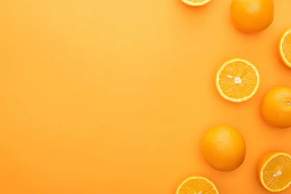 Vue de dessus des oranges entières juteuses mûres et des tranches sur fond coloré — Photo de stock