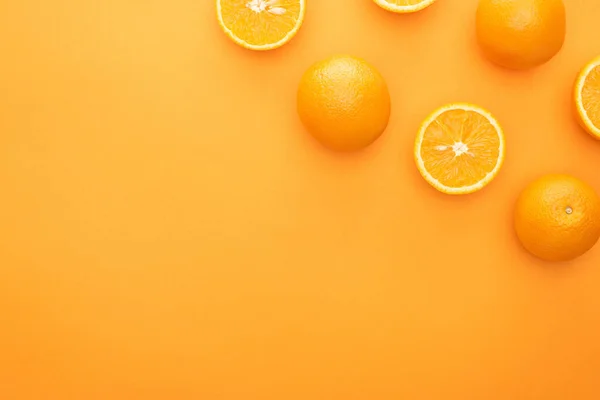 Vista superior de naranjas enteras jugosas maduras y rebanadas sobre fondo colorido - foto de stock