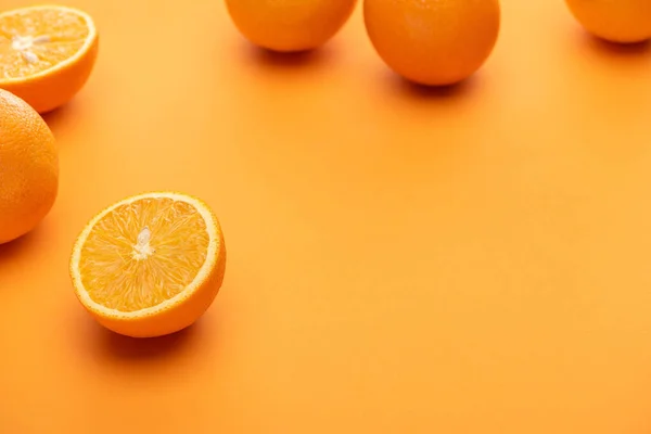 Selective focus of ripe juicy whole and cut oranges on colorful background — Stock Photo