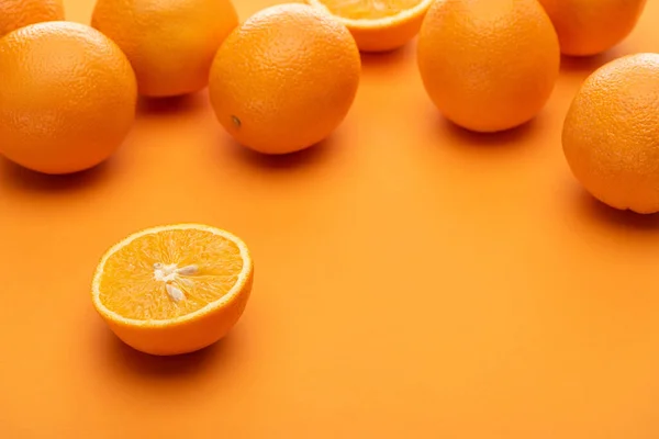 Ripe juicy whole and cut oranges on colorful background — Stock Photo