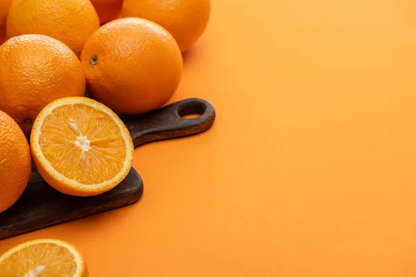 Frische saftige Orangen auf Schneidebrett auf buntem Hintergrund — Stockfoto