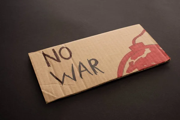 Cardboard placard with no war lettering and bomb on black background — Stock Photo