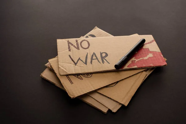 Marker on cardboard placard with no war lettering and bomb on black background — Stock Photo