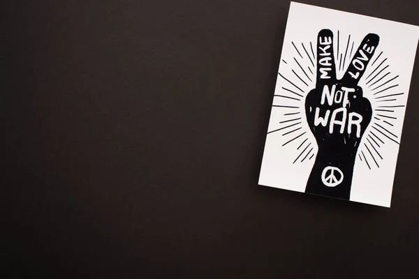 Vista dall'alto di carta bianca con disegno a mano, segno di pace e fare l'amore non lettere di guerra su sfondo nero — Foto stock