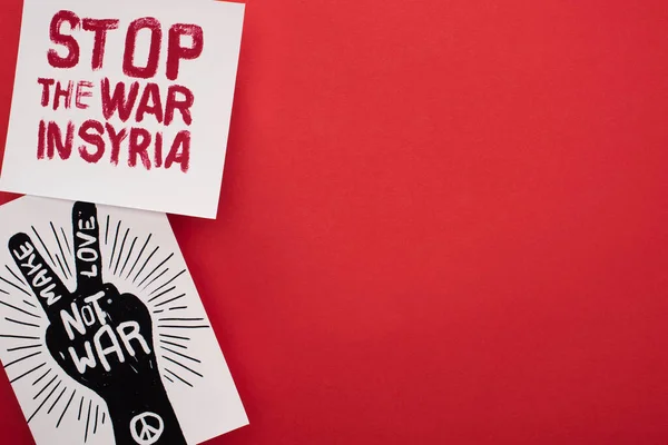 Top view of drawings with make love not war and stop war in Syria lettering on red background — Stock Photo