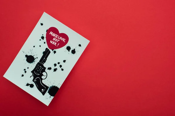 Draufsicht auf weißes Papier mit gezogenem schwarzen Revolver und Herz mit Make Love, nicht Kriegsschrift auf rotem Hintergrund — Stockfoto