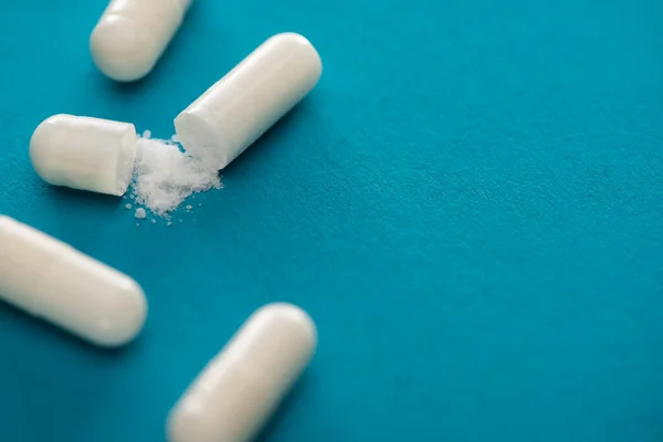 Close up view of probiotic capsules with white powder on blue background — Stock Photo