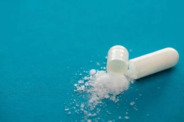 Close up view of probiotic capsule with white powder on blue background — Stock Photo