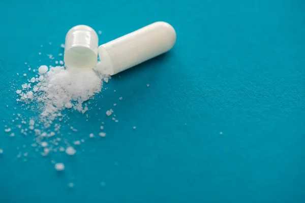 Close up view of probiotic capsule with white powder on blue background — Stock Photo