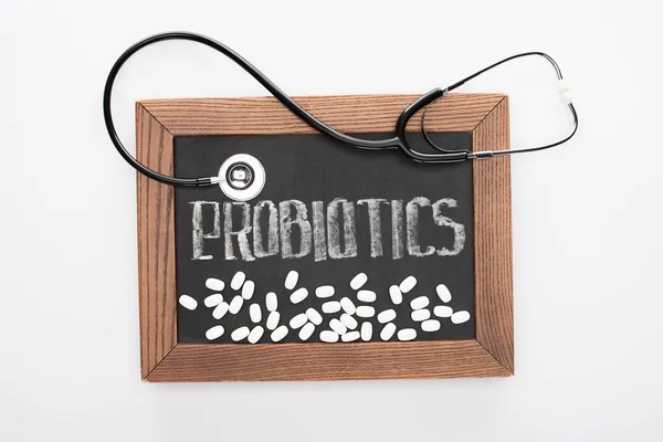 Top view of chalkboard with probiotics lettering with pills and stethoscope on white background — Stock Photo