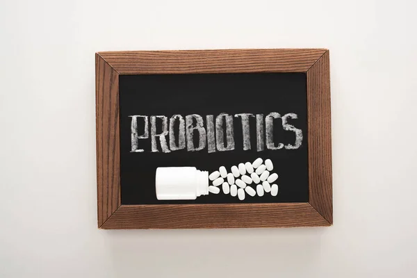 Vista superior do quadro com probióticos lettering com pílulas e recipiente sobre fundo branco — Fotografia de Stock