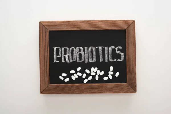 Top view of chalkboard with probiotics lettering with pills on white background — Stock Photo