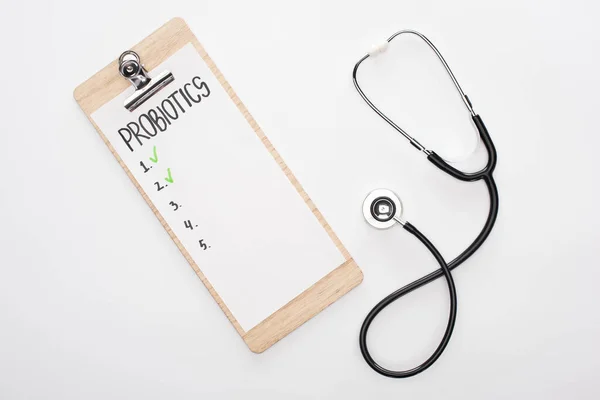 Vista dall'alto degli appunti con elenco vuoto di probiotici e stetoscopio su sfondo bianco — Foto stock