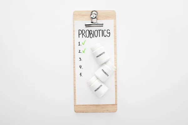 Top view of clipboard with probiotics empty list and pills on white background — Stock Photo