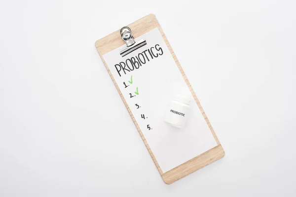 Top view of clipboard with probiotics empty list and pills on white background — Stock Photo