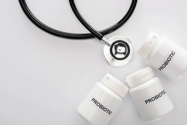 Top view of containers with probiotic lettering near stethoscope on white background — Stock Photo