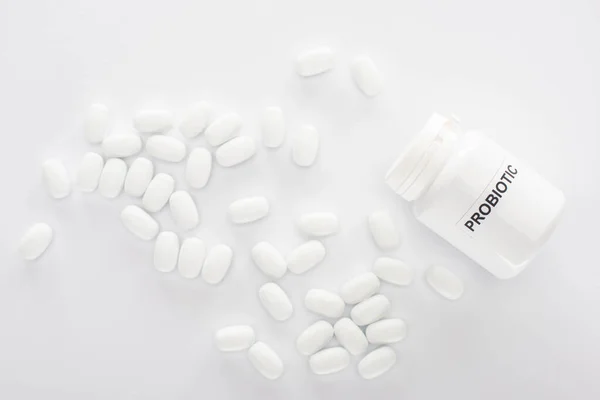 Top view of container with probiotic lettering near pills on white background — Stock Photo