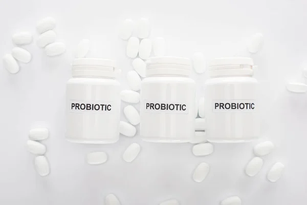 Top view of containers with probiotic lettering near pills on white background — Stock Photo