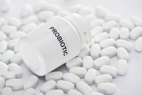 Selective focus of probiotic container near pills on white background — Stock Photo