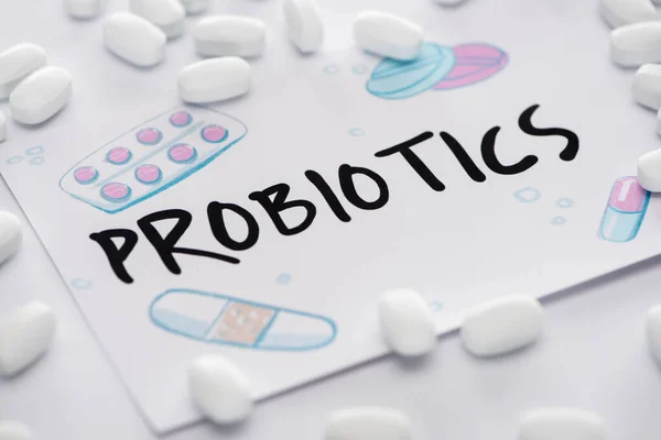 Enfoque selectivo de dibujo con letras de probióticos cerca de píldoras sobre fondo blanco - foto de stock