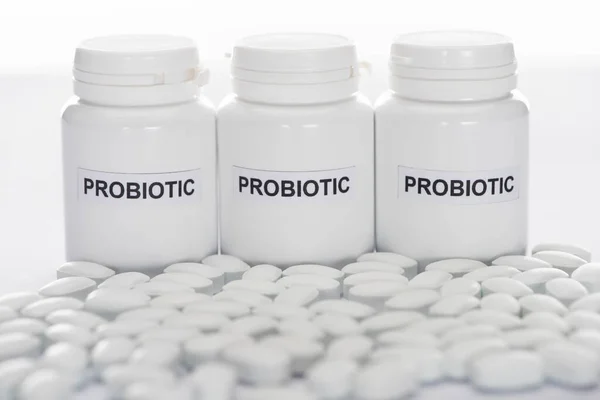 Selective focus of probiotic containers near pills on white background — Stock Photo