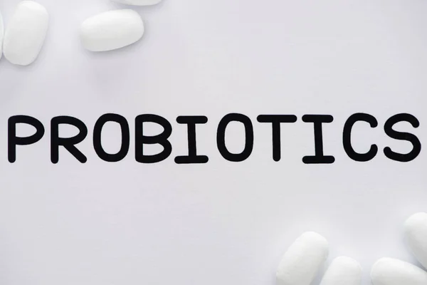 Top view of paper with probiotics lettering and pills on white background — Stock Photo