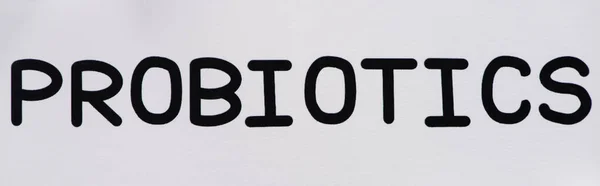 Top view of paper with probiotics lettering and pills on white background, panoramic orientation — Stock Photo