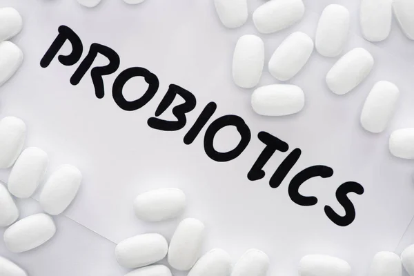 Top view of paper with probiotics lettering and pills on white background — Stock Photo