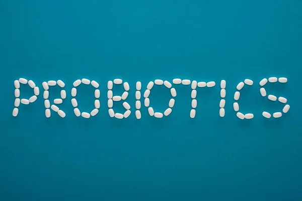 Top view of probiotics lettering made of pills on blue background — Stock Photo