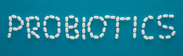 Vista superior de lettering probióticos feitos de pílulas em fundo azul, orientação panorâmica — Fotografia de Stock