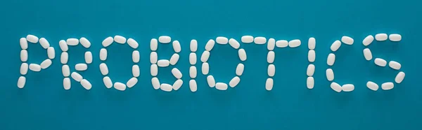 Top view of probiotics lettering made of pills on blue background, panoramic orientation — Stock Photo