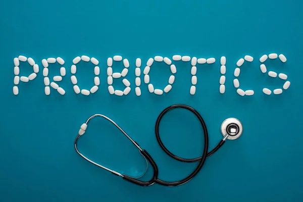 Top view of probiotics lettering made of pills and stethoscope on blue background — Stock Photo