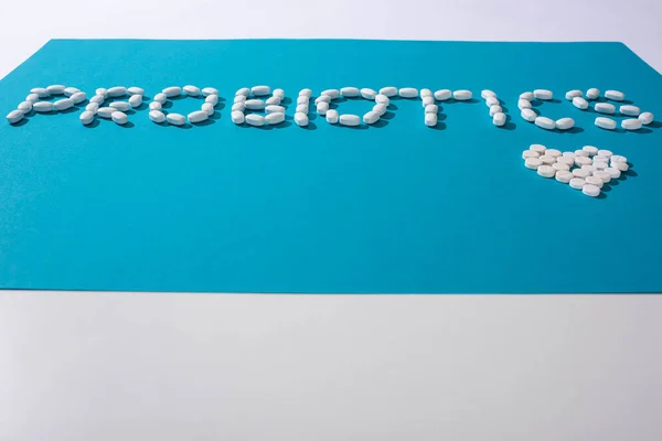 Probiotici lettering e cuore fatto di pillole su sfondo blu e bianco — Foto stock