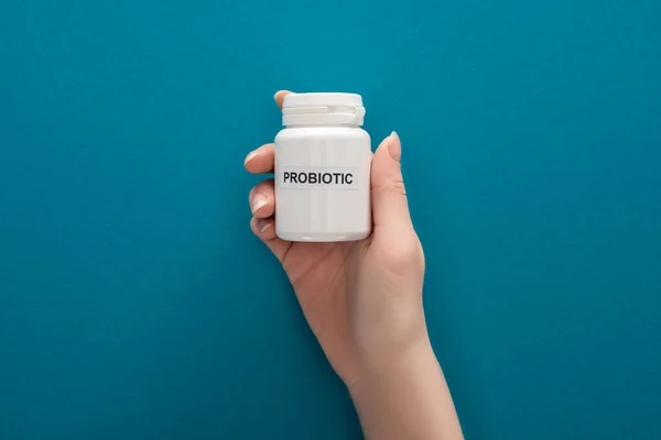 Vue recadrée de la femme tenant le récipient probiotique blanc sur fond bleu — Photo de stock